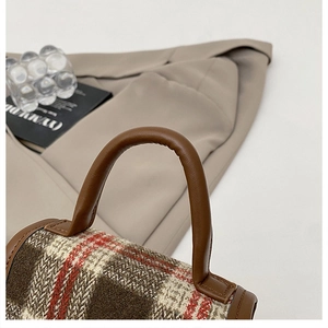 Detail of checkered plaid handbag featuring premium brown leather handle and stitching