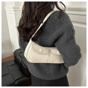 Détail du sac sous le bras en cuir crème avec deux poches à rabat et bandoulière réglable