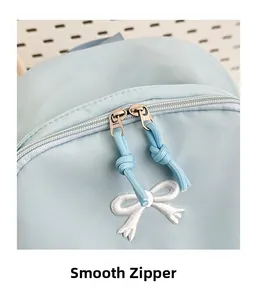 Detail of smooth metal double zippers and white bow embroidery on light blue backpack