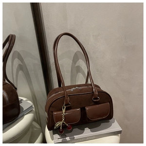 Detail of dark brown baguette bag featuring front flap pockets and cherry pendant accessory