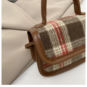 Close-up of classic plaid wool fabric and premium brown leather piping on a mini handbag