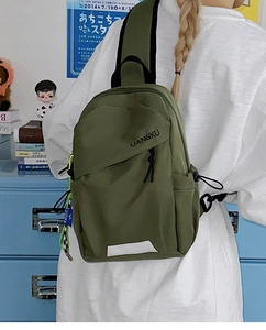 Détail du sac de poitrine en nylon vert olive avec bande réfléchissante et breloques