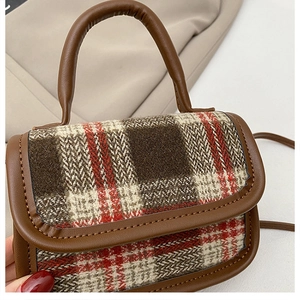 Close-up of retro plaid pattern handbag with brown leather trim and detailed texture