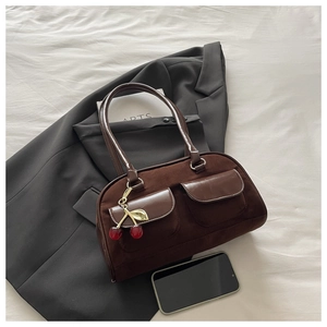 Close-up of vintage brown suede bowling bag featuring cherry charm and dual front pockets