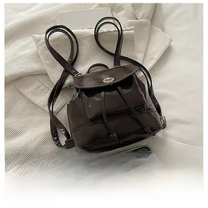 Close-up of a mini brown faux leather backpack with gold twist lock and size reference