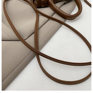 Detail of the brown faux leather handle and strap with premium stitching on a handbag