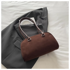 Close-up of dark brown suede baguette bag with smooth leather handle and silver metal hardware