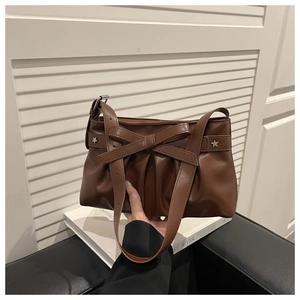 Details einer braunen Plissee-Schultertasche mit großer Schleife und silbernen Sternnieten