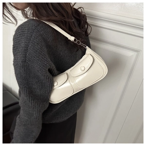 Vue détaillée du sac sous le bras vintage crème avec poches sur un pull gris