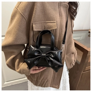 Dettaglio mini borsa a tracolla nera con fiocco grande e borchie a stella in argento