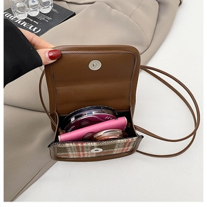 Detail view of the open plaid crossbody bag showing internal storage space and magnetic snap