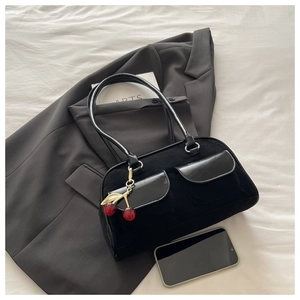 Detail of black baguette bag with suede leather mix and cherry charm on stylish suit
