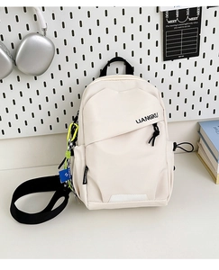 Détail d'un sac à dos en nylon crème avec poche zippée et logo de la marque en noir