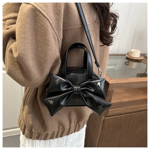 Détail du petit sac noir brillant orné d'un grand nœud et de clous en forme d'étoile