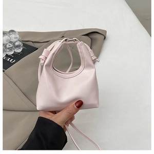 Detailed view of a light pink mini PU leather handbag with unique circular handle