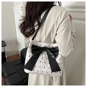 Detail of white quilted tote bag featuring black bow accent and rabbit embroidery
