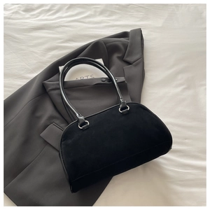 Close-up of black suede and smooth leather baguette bag with silver ring hardware