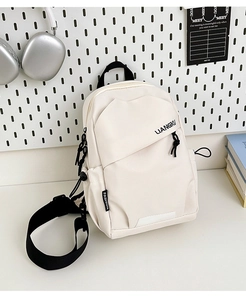 Gros plan d'un sac de poitrine en nylon beige avec fermetures éclair noires et logo