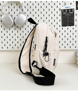 Détail du sac bandoulière blanc cassé avec étiquette de mode et sangle en nylon noir