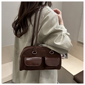 Detailed side view of a vintage coffee brown suede baguette bag worn by a model
