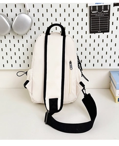 Détail d'un sac de poitrine en toile blanc cassé avec une sangle noire sur un bureau