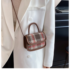 Détail d'un sac bandoulière vintage à carreaux avec bordures en cuir marron et motif