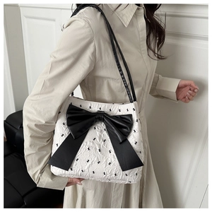 Detail view of white shoulder bag featuring 3D texture and large black leather bow