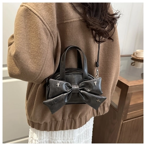 Détail du sac seau en cuir mat noir avec nœud décoratif et clous en forme d'étoile