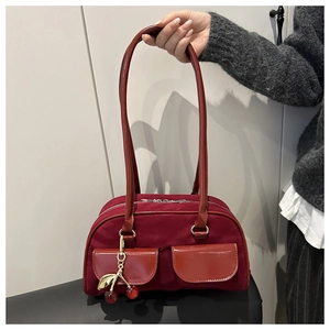 Detail of vintage burgundy baguette bag with dual pockets and gold cherry charm