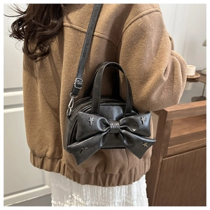 Détail du sac noir avec grand nœud et rivets d'étoiles porté par le mannequin