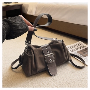 Détail d'un sac hobo vintage marron foncé avec plis rétro et ceinture à œillets métalliques