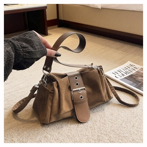 Gros plan d'un sac bandoulière en daim marron avec large sangle et boucle métallique