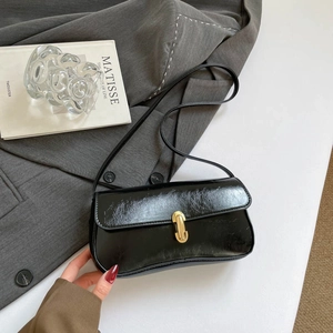 Sac baguette en cuir verni noir de style français avec boucle dorée sur fond chic