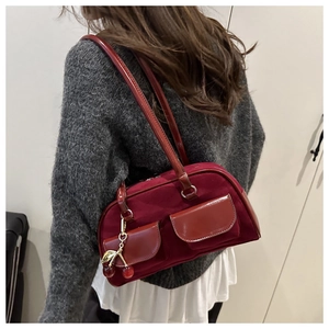 Close-up of burgundy Boston bag showing suede and patent leather contrast with cherry charm