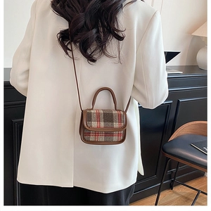 Model wearing a vintage plaid shoulder bag with brown leather trim over a white blazer