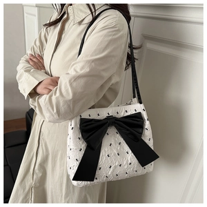 Detail of white bucket bag with black floral pattern and large decorative silk bow