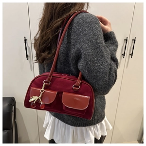 Detail of burgundy baguette bag with dual pockets and metal cherry charm accessory