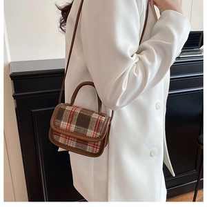 Detailed shot of a retro plaid crossbody bag with brown leather trim on a model