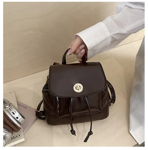Détail d'un mini sac à dos marron foncé avec fermoir rotatif romain doré et cordon de serrage