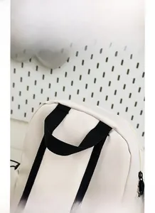 Détail de la poignée noire confortable sur un sac à dos blanc à la texture lisse