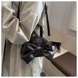 Détail d'un sac seau marron foncé avec un grand nœud et des clous étoilés argentés