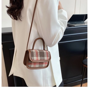 Détail du rabat en tissu à carreaux et de l'anse en cuir marron sur un sac bandoulière