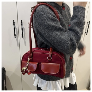 Detail of dark red baguette bag featuring double front pockets and cherry charm