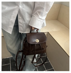 Detail of dark brown leather mini backpack with gold twist lock and drawstring closure