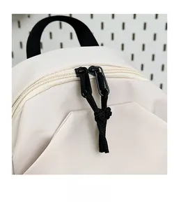 Détail des fermetures éclair fluides avec tirettes à nœuds noirs sur un sac crème