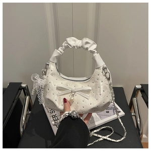 Close-up of white ruffled handle bag featuring rhinestone bows and pearl pendants