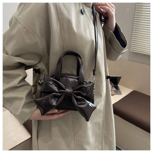 Détail du sac à bandoulière marron foncé avec nœud et rivets étoiles sur cuir de qualité
