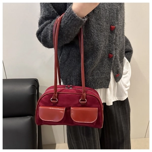Detail view of burgundy baguette bag with dual pockets and metallic silver ring accents