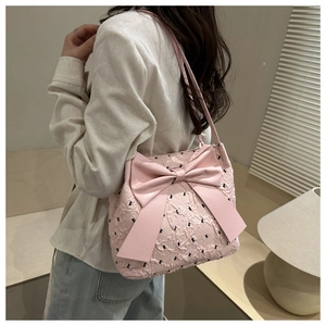 Lifestyle shot of pink pleated shoulder bag with black bows and large bow detail