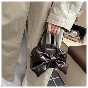 Détail du sac seau marron café avec un grand nœud et des clous métalliques en étoile